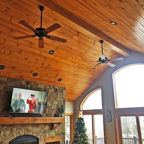 A living room with a Christmas tree in it with almond v groove paneling. 