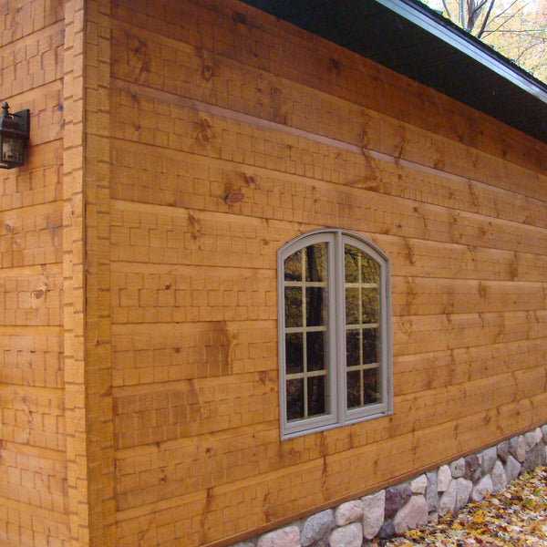 A house with the adaze siding in the woods with a stone basement. 