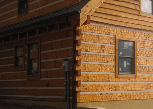 The adze siding shows its value with natural light glaring upon it, while the white chinking strips offer a nice balance between the siding.