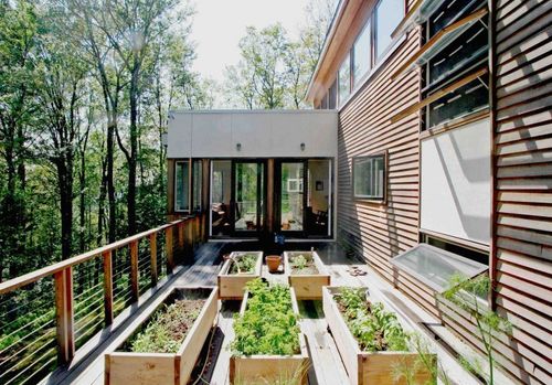 House completed with beveled cedar siding. Raised flower beds on the deck and a railing. 