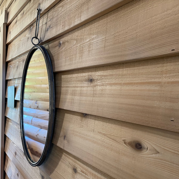 Close up of beveled cedar siding with a mirror hanging on it. 