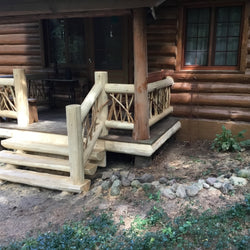 A bright cedar half log staircase enhances the entry way to this rustic cabin.
