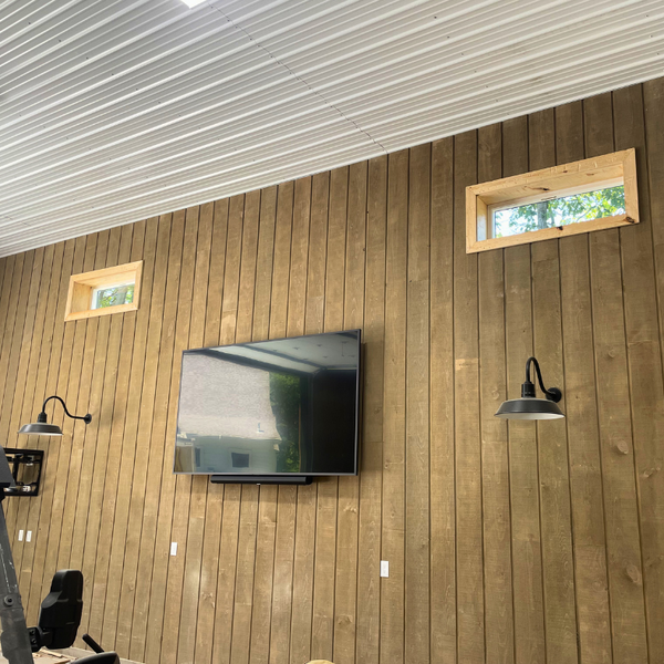 Channel rustic siding with a TV hanging on the wall and windows letting in natural light.