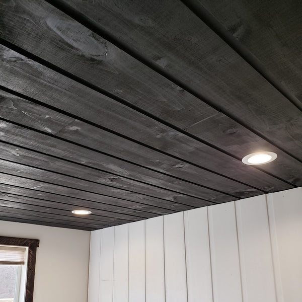 Channel rustic siding on the ceiling of a home with white walls and a rustic window.