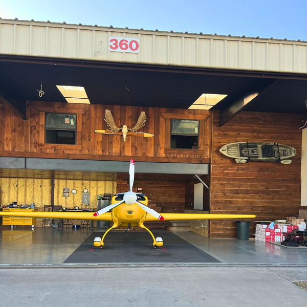 A plane sitting in front of a building which is sided with channel rustic siding.