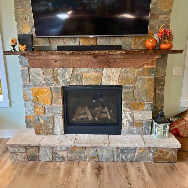 Fire place with a TV above it completed wit ha hardwood slab mantel and decorated for fall. 