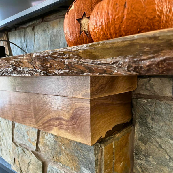 Hardwood slab being used as a mantel above a fire place with pumpkins sitting on it. 
