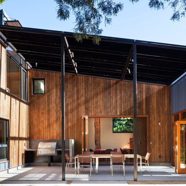 Kebony siding used for the house and outdoor patio. The outdoor patio has a grill and table and looks into and indoor seating room. 