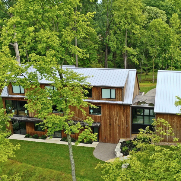 The back side of a house with Kebony siding. Their are trees and landscaping and a sidewalk.