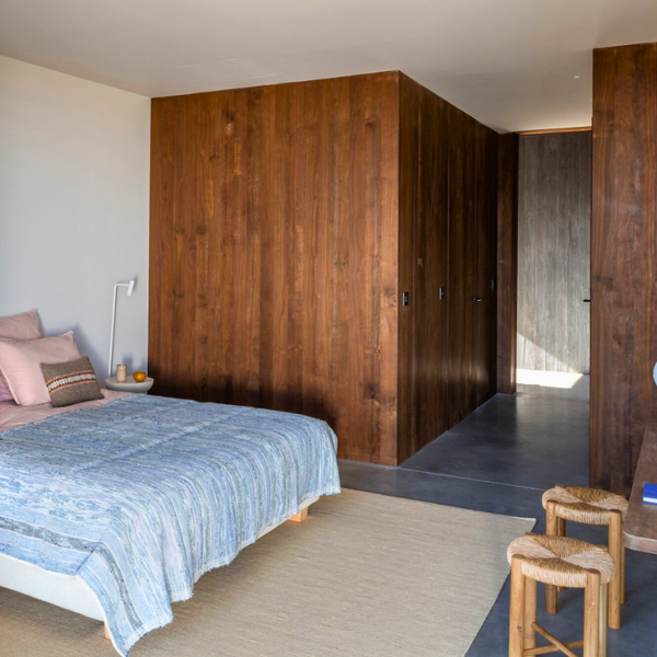 A bedroom with a bed placed in the middle having a desk. The room is completed with Kebony siding and a white accent wall. 