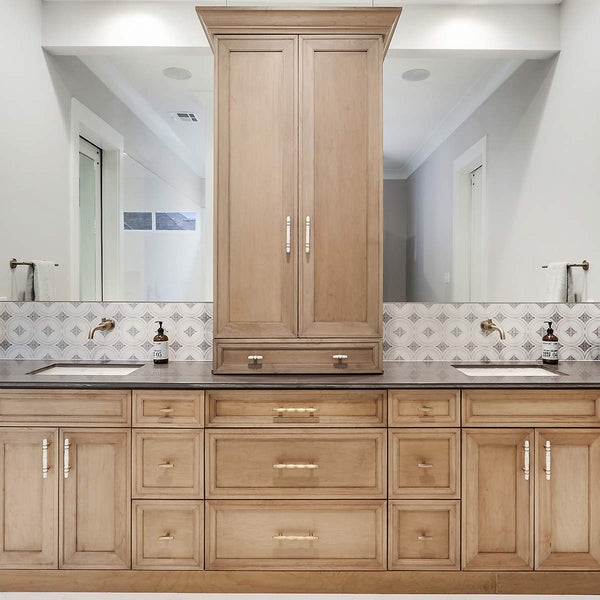 countertop with brown Kith One Cabinetry. A big mirror that stretches the width of the wall and a dark countertop.  