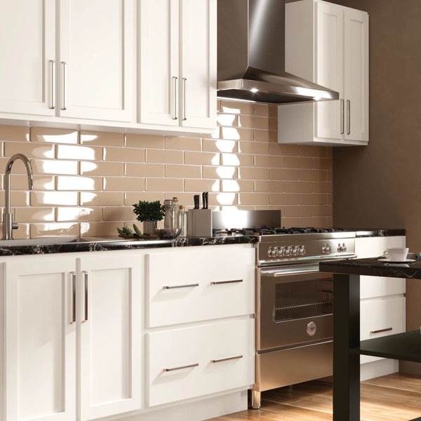 A very classy simple kitchen with white mantra cabinets and grey appliances. These are surrounding a small island with pancakes and coffee on it. 