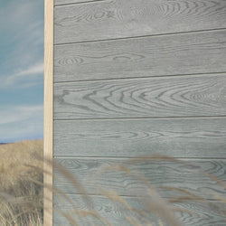 Grey Millboard Envello siding on a house corner on the beach. 
