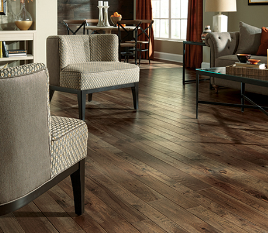 Living room with a couch and two chairs surrounding a coffee table with red accents throughout the room. All complete the Somerset hardwood flooring. 