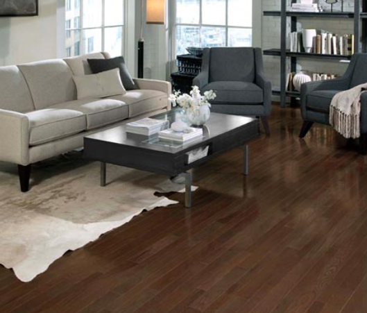 Living room with a white couch and two grey chairs surrounded by a coffee table and rug. Completed with Somerset hardwood flooring.