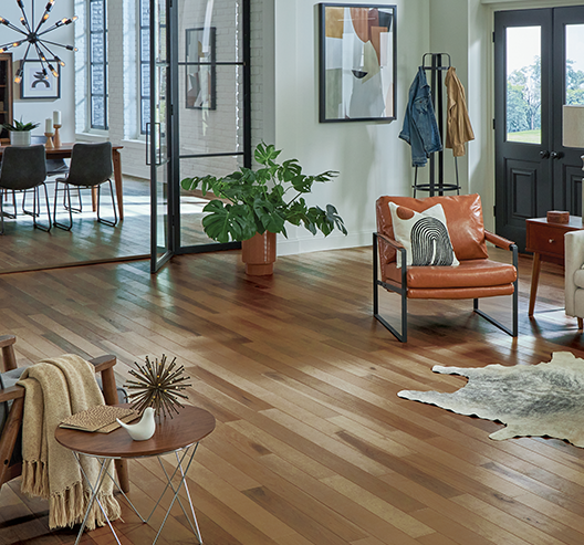 Living area with Somerset Hardwood flooring. A orange sitting chair and rug are centered in the room.