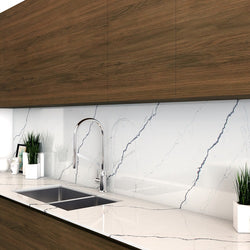 Brown cabinets with Vicostone Quartz countertops in a simplistic kitchen. Plants and decor on the counter with a stainless steel sink.