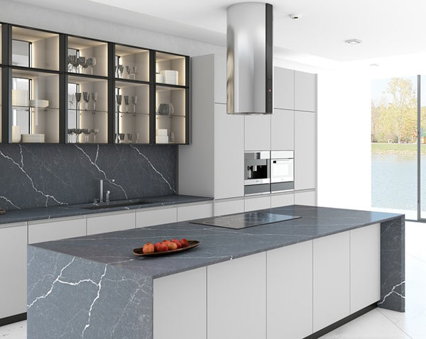 A simplistic kitchen with black Vicostone Quartz countertops and flat electric stovetop. There are grey cabinets and stainless steel sink. 