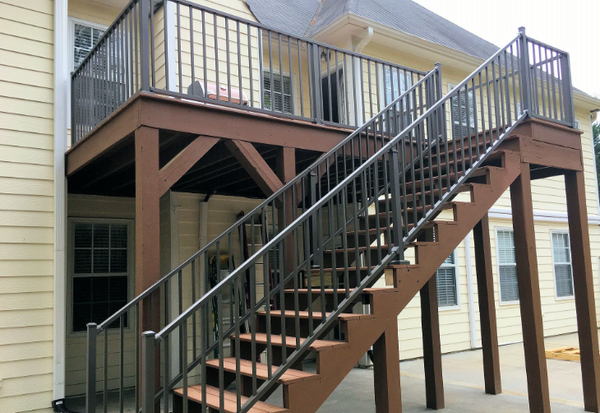 Brown deck connected to a yellow house completed with Westbury Aluminum railing.