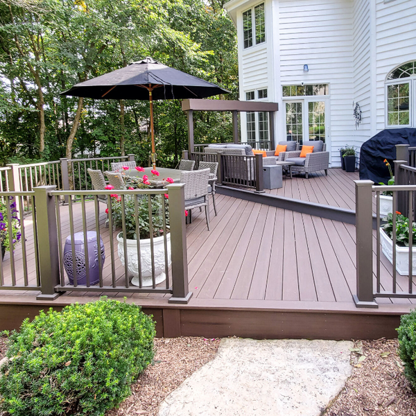 White house with a a full deck that has two seating areas and flower pots on it. The deck is completes with a Westbury Aluminum railing. 