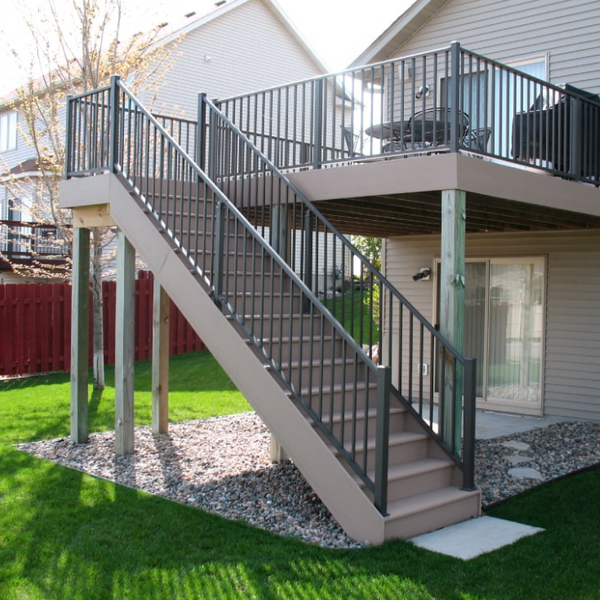 Brown house with a raised deck and staircase with a seating area and gill on it. It is completed with Westbury Aluminum railing. 
