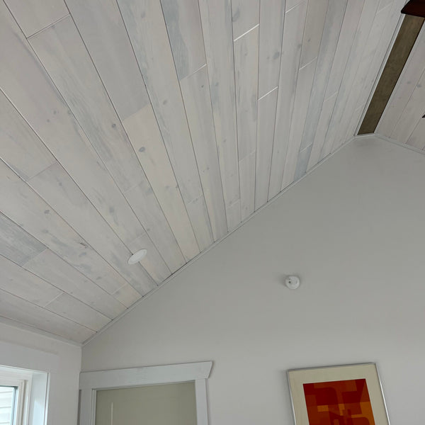 A room with white pine nickel gap paneling on the ceiling. 