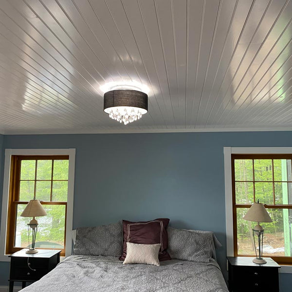 Bedroom with blue walls. The bed has two night stands on each side and a modern light fixture on the center of the room. The ceiling is completed with white pine tongue and groove pre finish. 