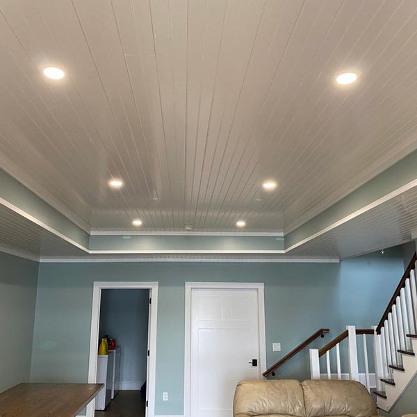 Basement with blue walls looking into a laundry room. Completed with white pine tongue and groove ceiling. 