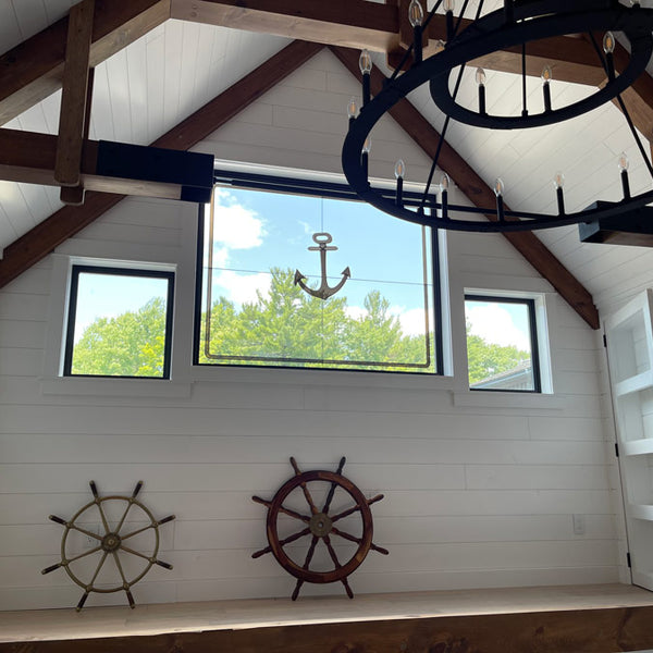 Unique room with white pine tongue and groove pre finish. An achor hanging in the window and two wheels leaned up against the wall. 