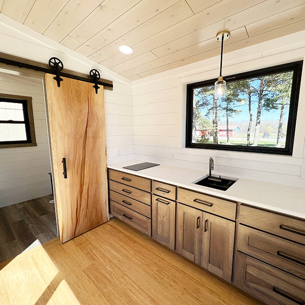 Minimalistic bathroom completed with brown cabinetry, a sliding door and white pine tongue and groove walls. 