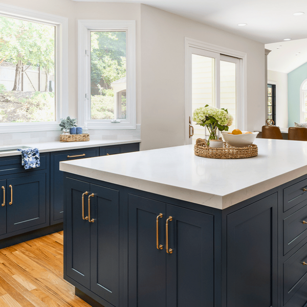 Kitchen cabinets in naval blue with gold accents and white countertops.